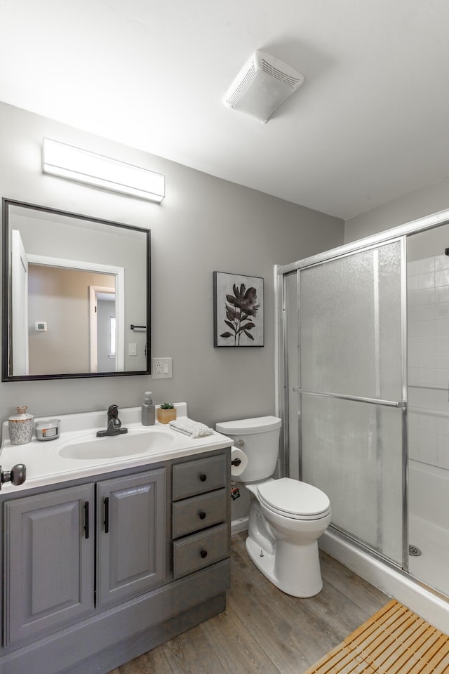 bathroom featuring visible vents, a shower stall, toilet, wood finished floors, and vanity