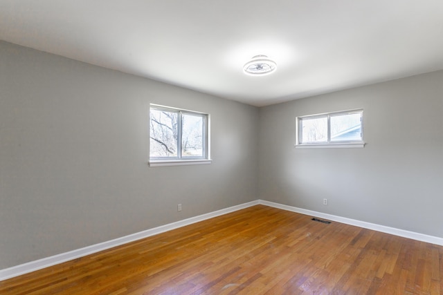 empty room featuring visible vents, baseboards, and wood finished floors