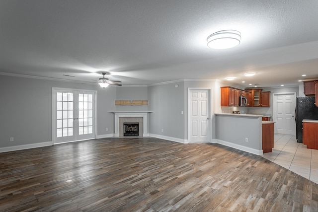 unfurnished living room with baseboards, dark wood finished floors, a tiled fireplace, and ornamental molding