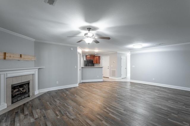 unfurnished living room featuring ornamental molding, a tile fireplace, and dark wood-style flooring