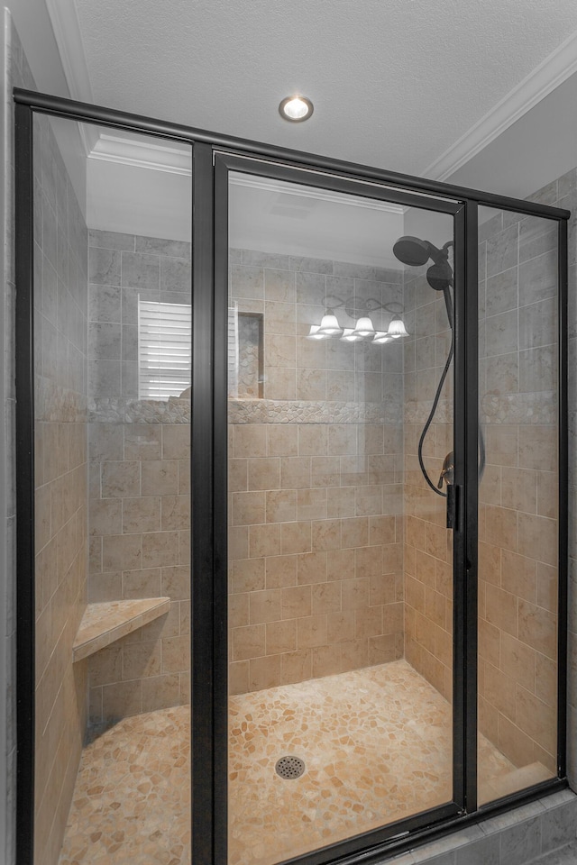 full bathroom featuring a textured ceiling, a stall shower, and crown molding