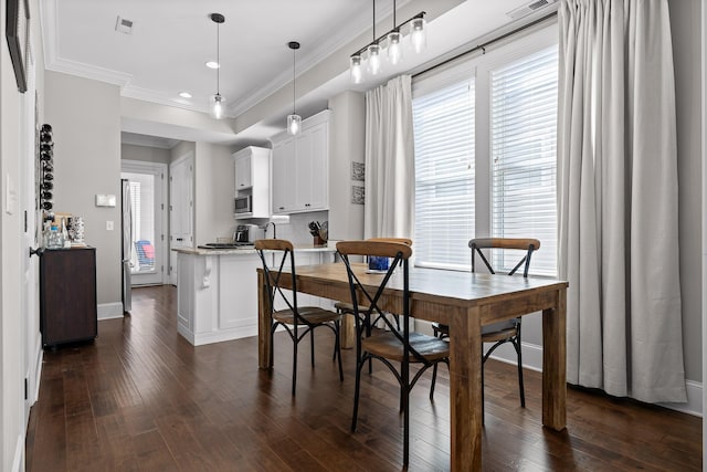 dining space featuring baseboards, dark wood-type flooring, a raised ceiling, and crown molding