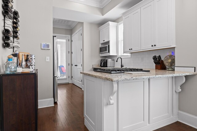 kitchen with appliances with stainless steel finishes, white cabinets, crown molding, and light stone countertops