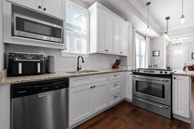 kitchen featuring crown molding, appliances with stainless steel finishes, white cabinets, a sink, and a peninsula