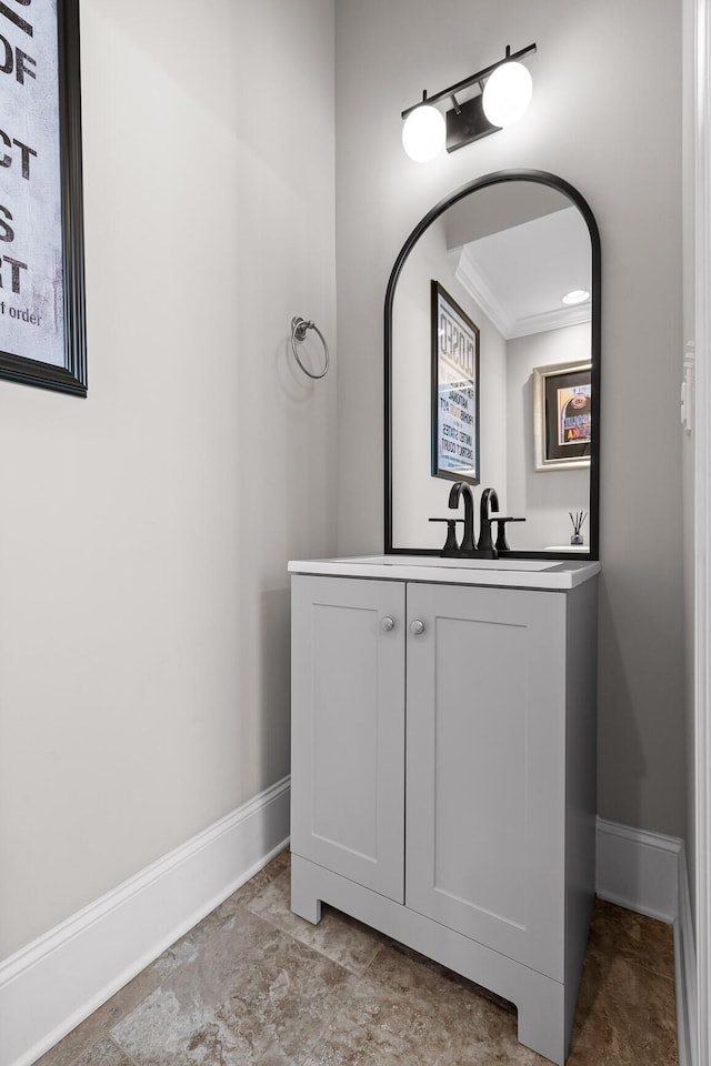 bathroom featuring a sink, crown molding, and baseboards