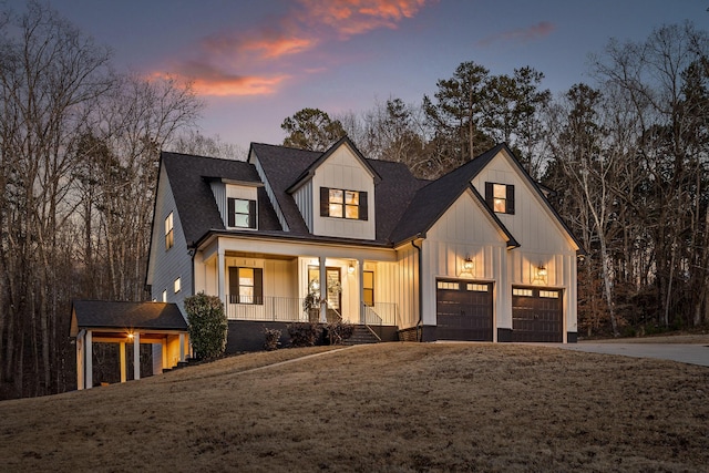 modern farmhouse featuring driveway, covered porch, a shingled roof, a garage, and board and batten siding