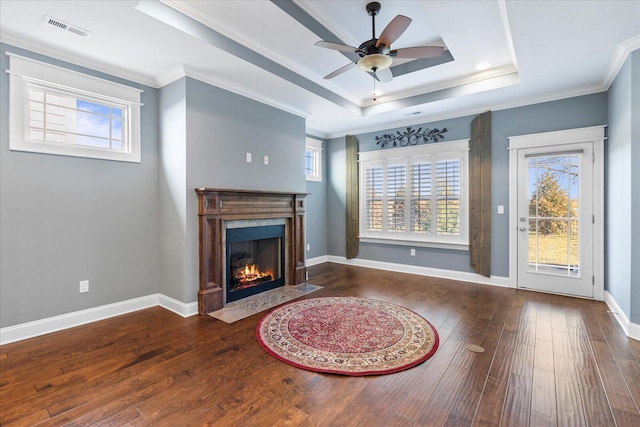 living area featuring a healthy amount of sunlight, wood-type flooring, a raised ceiling, and a fireplace with flush hearth