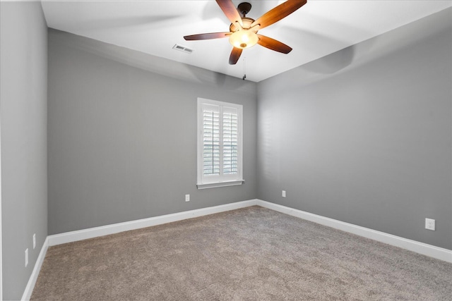 empty room with carpet floors, a ceiling fan, visible vents, and baseboards