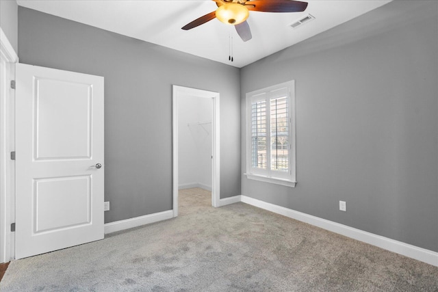 unfurnished bedroom featuring carpet floors, a closet, visible vents, a spacious closet, and baseboards