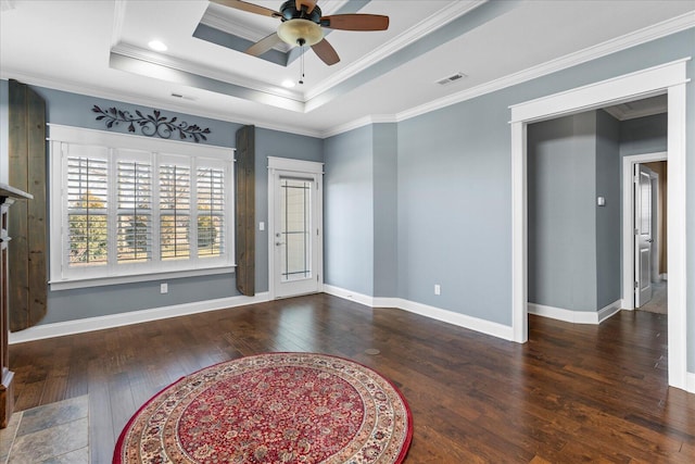 empty room featuring visible vents, baseboards, hardwood / wood-style floors, a raised ceiling, and crown molding