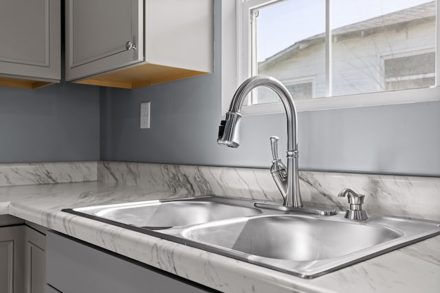 details with gray cabinets, a sink, and light countertops