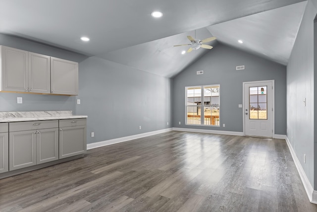 unfurnished living room with ceiling fan, lofted ceiling, dark wood-type flooring, visible vents, and baseboards