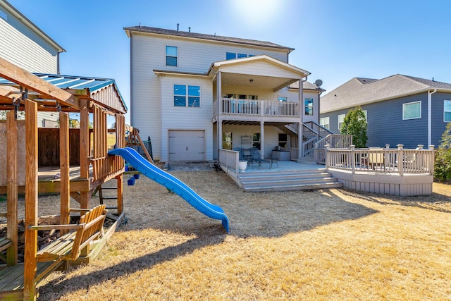 back of property featuring a wooden deck, a garage, driveway, and a playground