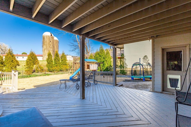 wooden terrace with a trampoline and fence