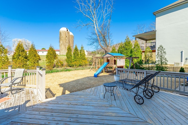 wooden deck with a playground and fence