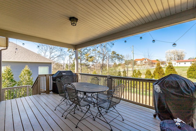 wooden terrace with outdoor dining area and grilling area