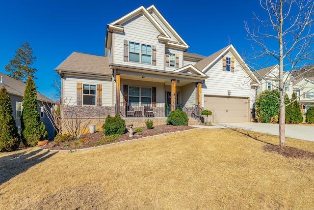 craftsman house featuring a front yard, driveway, roof with shingles, an attached garage, and covered porch