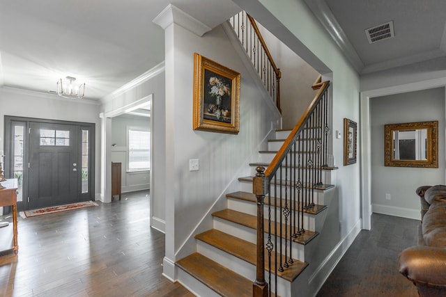 foyer entrance featuring baseboards, wood finished floors, visible vents, and ornamental molding