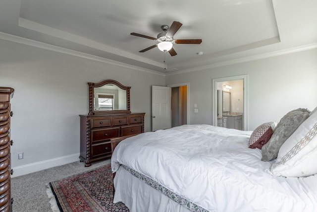 bedroom featuring ensuite bath, carpet flooring, baseboards, and a tray ceiling