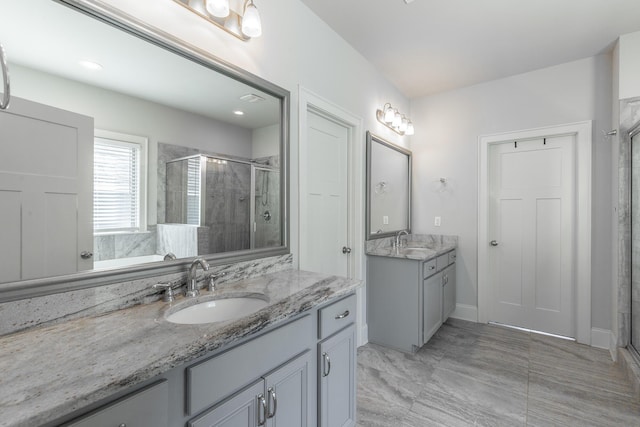 bathroom with a shower stall, two vanities, and a sink