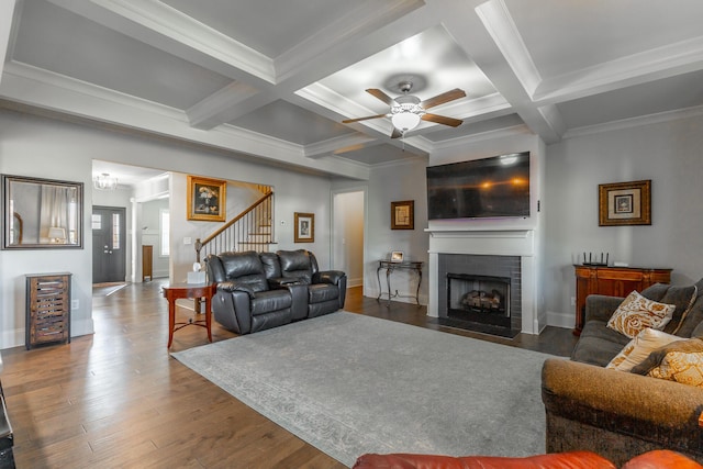 living room with stairway, wood finished floors, coffered ceiling, beam ceiling, and a fireplace with flush hearth