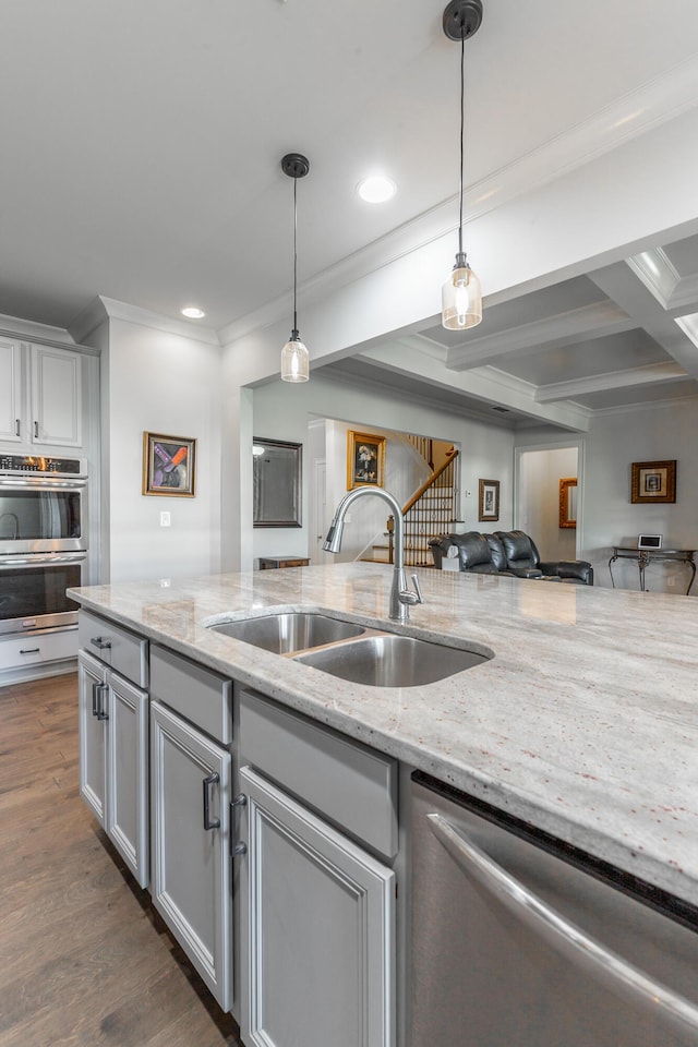 kitchen featuring dark wood finished floors, a sink, stainless steel appliances, crown molding, and decorative light fixtures