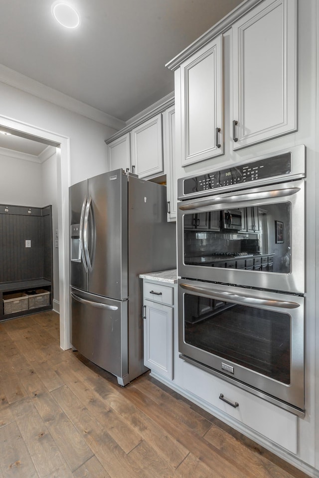 kitchen featuring light stone countertops, stainless steel appliances, crown molding, and dark wood-style flooring