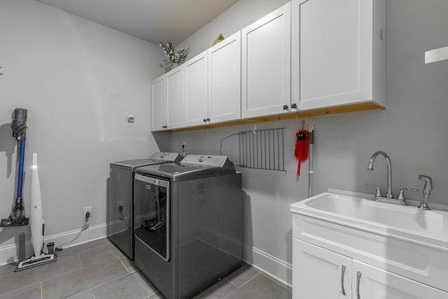 washroom with washer and dryer, a sink, cabinet space, light tile patterned floors, and baseboards