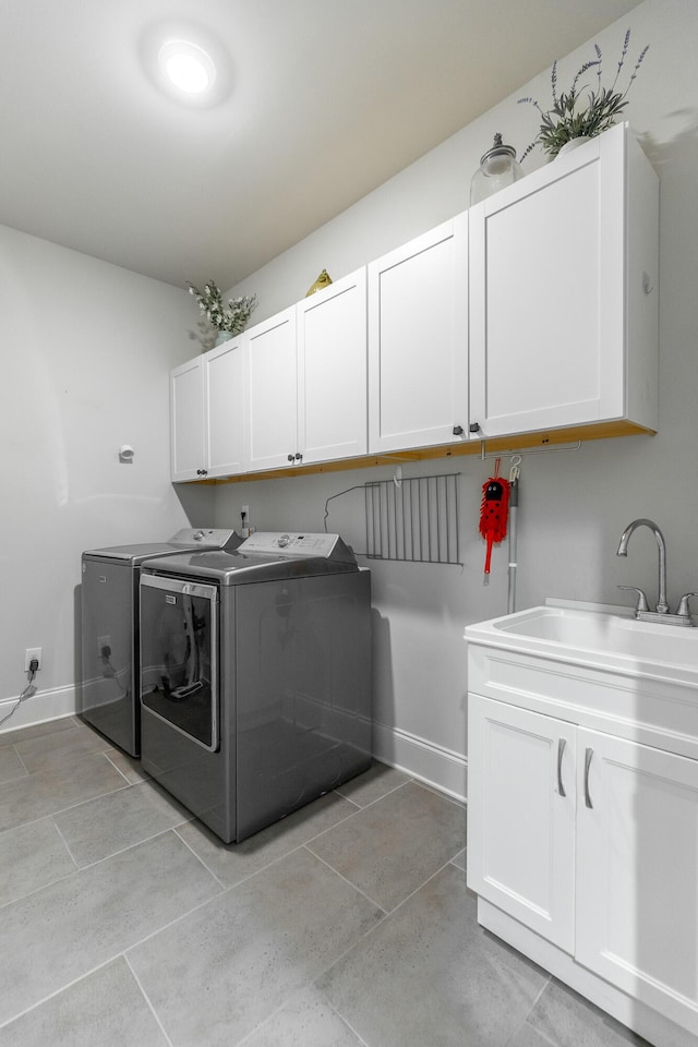 washroom featuring a sink, baseboards, cabinet space, and washing machine and clothes dryer