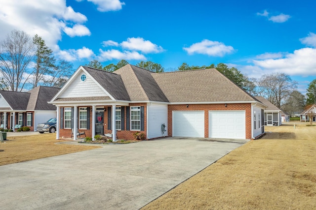 view of front of home featuring driveway, roof with shingles, a front lawn, and brick siding