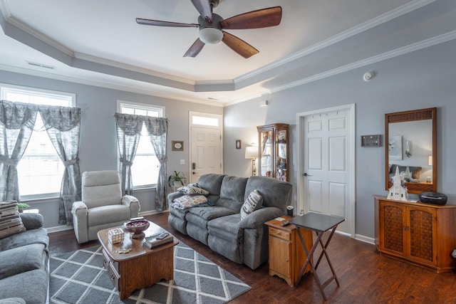 living room featuring baseboards, visible vents, wood finished floors, a tray ceiling, and crown molding