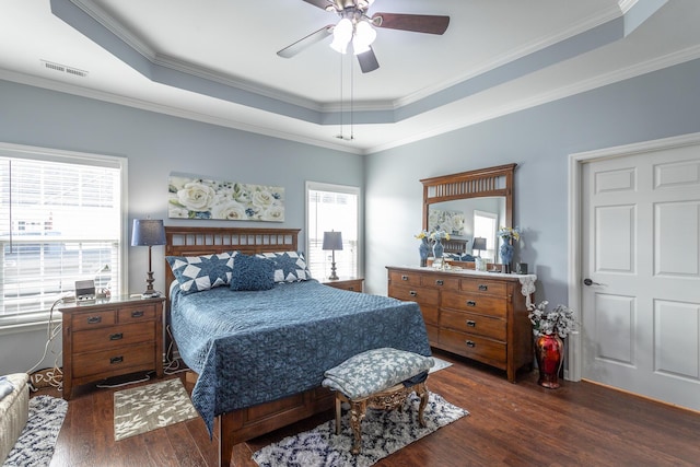 bedroom featuring ornamental molding, dark wood-type flooring, a raised ceiling, and visible vents