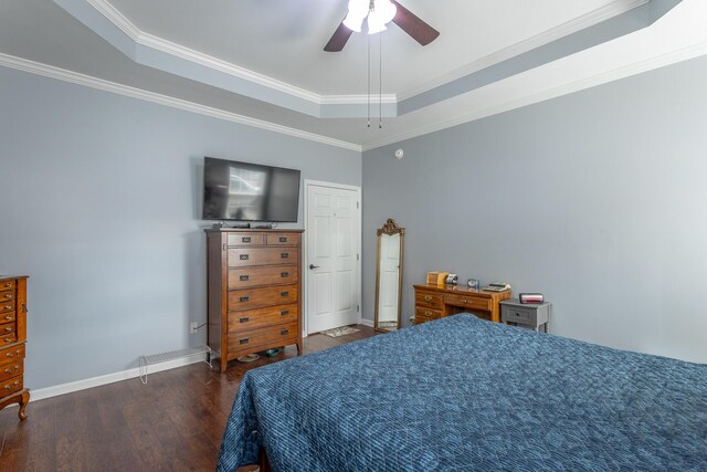 bedroom with dark wood-type flooring, a raised ceiling, ornamental molding, and baseboards