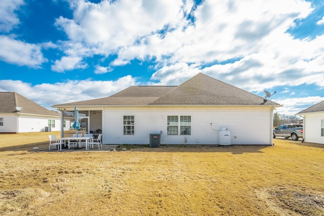 rear view of property with a shingled roof, a lawn, a patio area, and central air condition unit