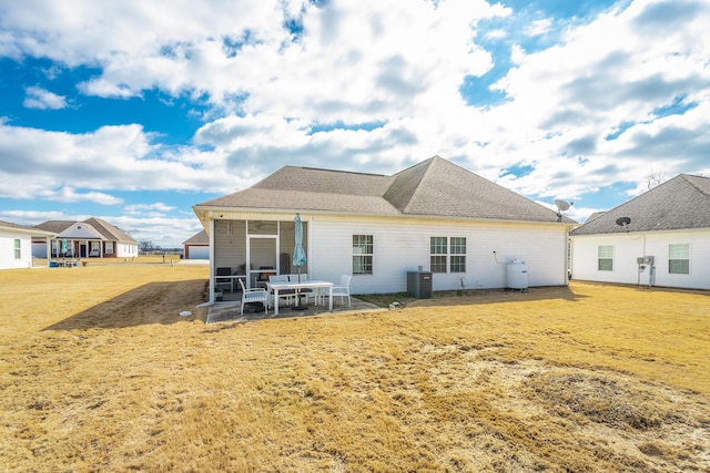 back of property featuring roof with shingles, a yard, central AC unit, a sunroom, and a patio area