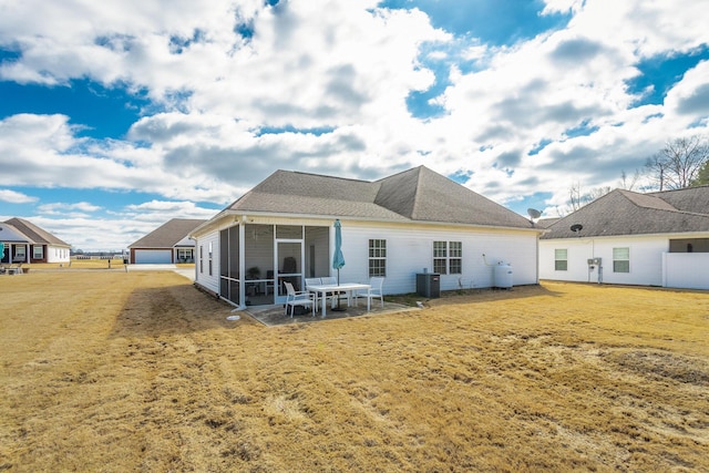 back of house featuring a sunroom, a lawn, and central air condition unit