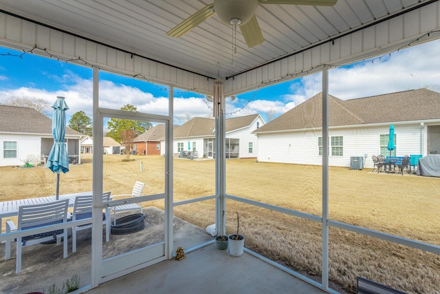 unfurnished sunroom featuring ceiling fan and a residential view