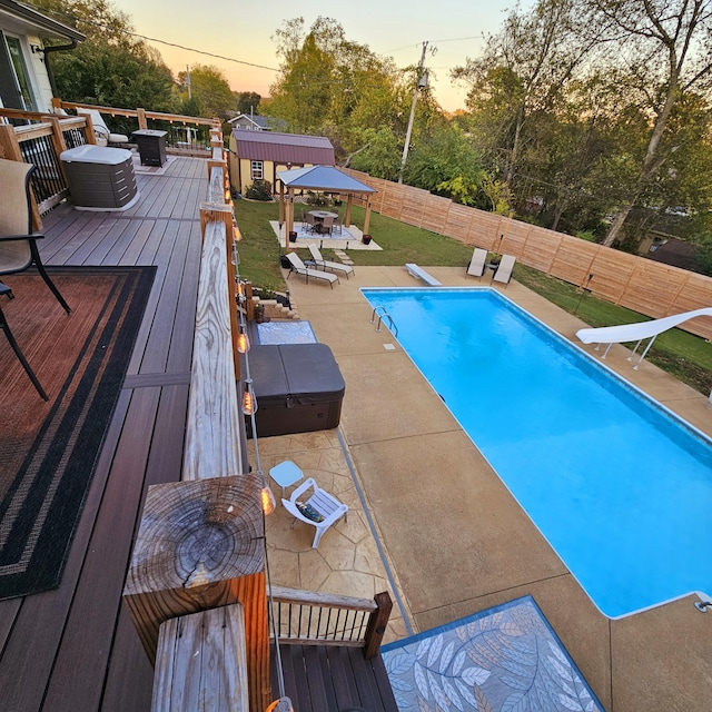 pool at dusk featuring a fenced in pool, a yard, a deck, a fenced backyard, and a diving board