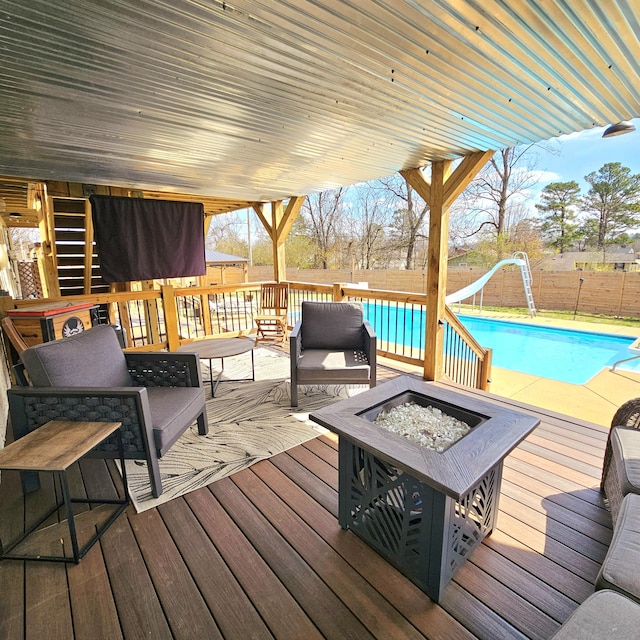 wooden deck with a fenced in pool, an outdoor living space with a fire pit, and fence