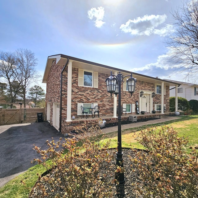 view of front facade with driveway, a garage, fence, and brick siding