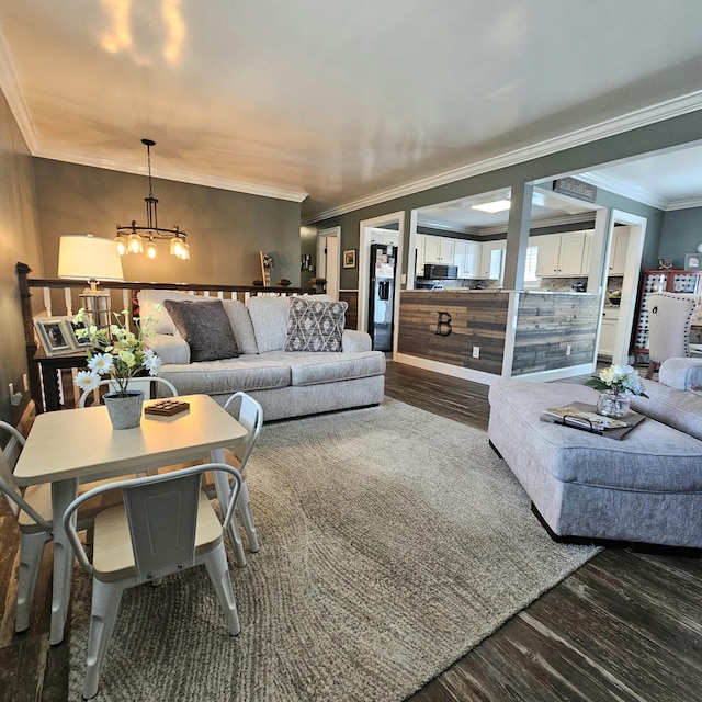 living area with dark wood-style flooring, crown molding, and an inviting chandelier