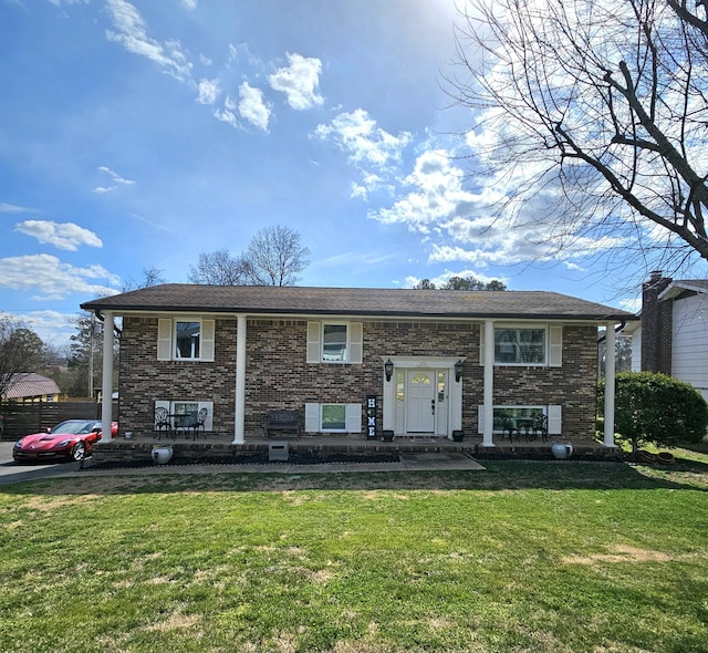 raised ranch featuring a front lawn and brick siding