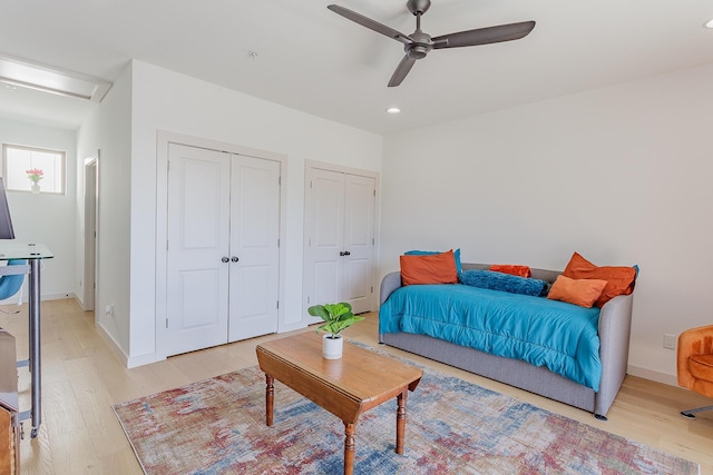 bedroom with light wood finished floors, baseboards, and multiple closets