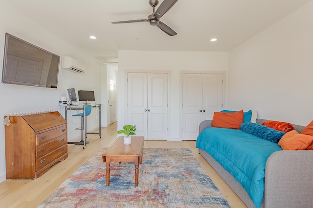 bedroom featuring ceiling fan, recessed lighting, multiple closets, light wood-type flooring, and a wall mounted air conditioner