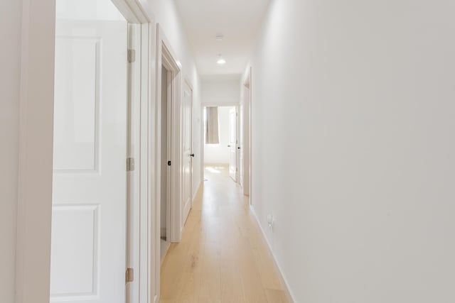 hallway with recessed lighting, baseboards, and light wood finished floors