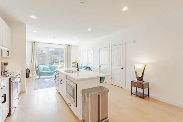 kitchen with light wood finished floors, stainless steel appliances, a sink, and recessed lighting