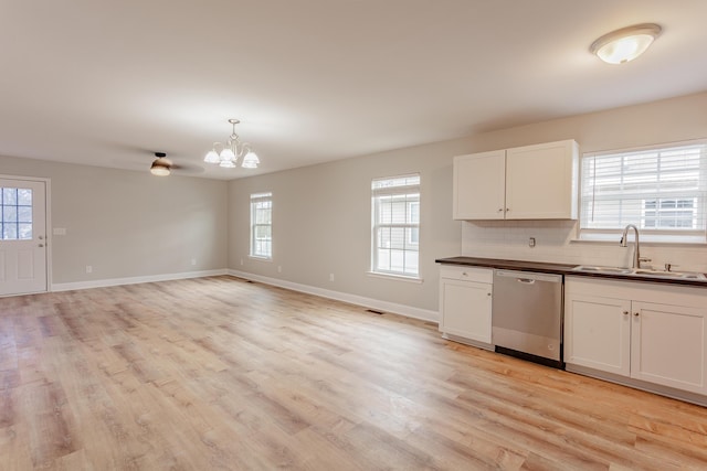 kitchen featuring tasteful backsplash, stainless steel dishwasher, white cabinets, a sink, and light wood-type flooring