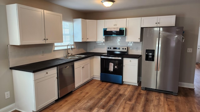 kitchen with tasteful backsplash, appliances with stainless steel finishes, a sink, and white cabinets