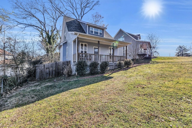 bungalow featuring covered porch, fence, a front lawn, and roof with shingles