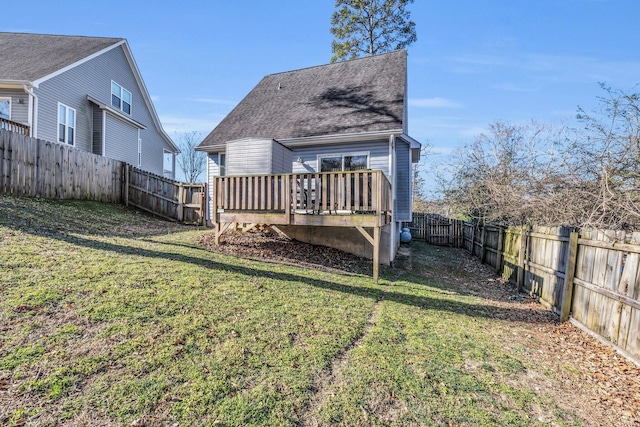 back of property featuring a fenced backyard, a yard, a wooden deck, and roof with shingles